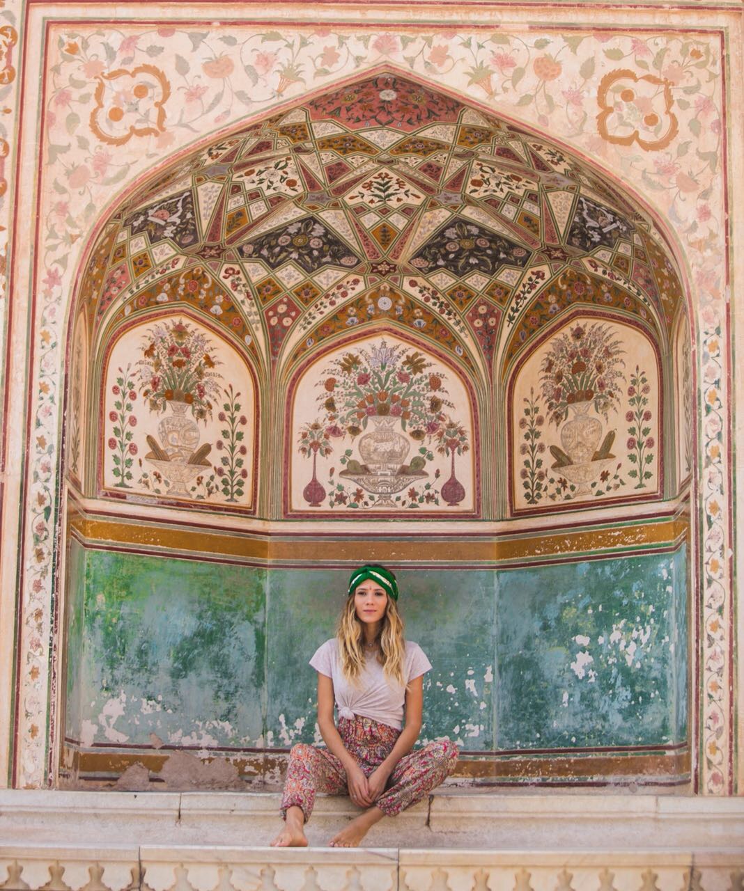 Nina sentada sob um arco florido pintado à mão, Amber, Jaipur