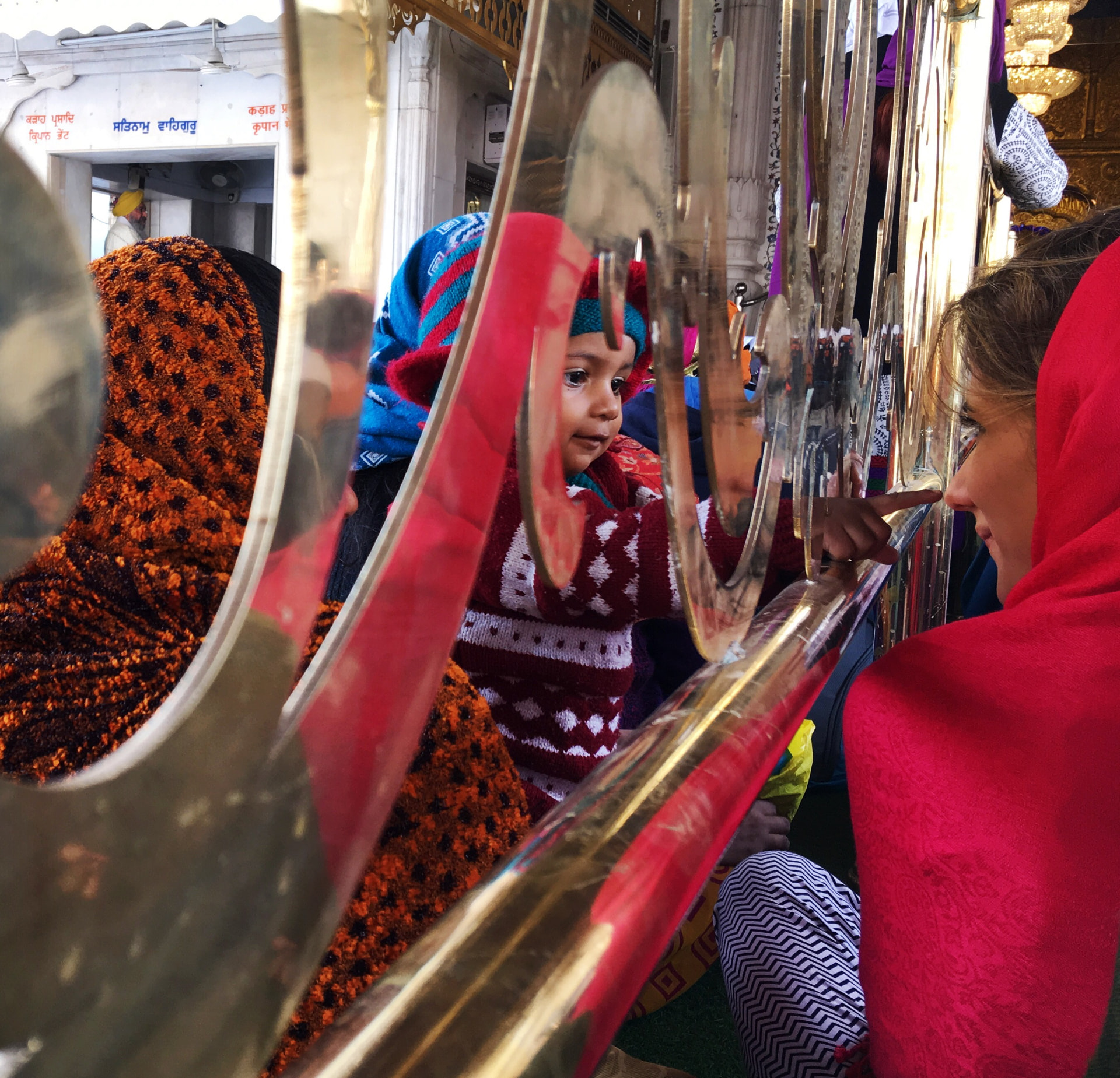 Nina tocando os espelhos dourados de um templo, com uma criança ao lado