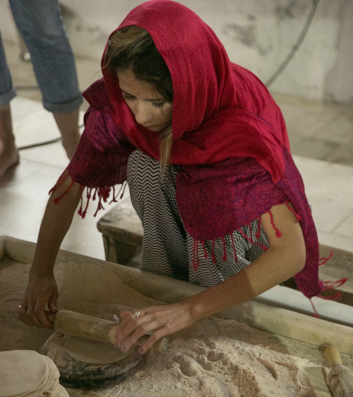 Nina moendo grãos na pedra dentro de um templo